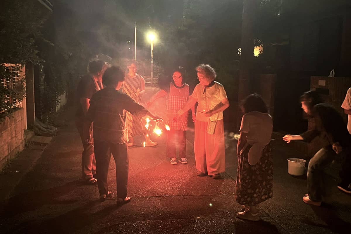 夜、老若男女の数人で手持ちの花火を楽しんでいる。